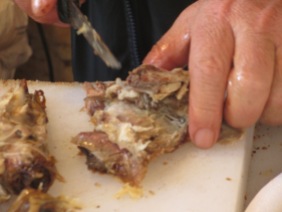 man's hand and knife pulling meat apart
