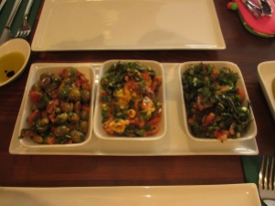 three dishes on a larger white plate with salads