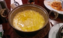 metal dish with yellow melted cheese and butter