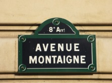 Paris street sign of Ave Montaigne blue sign with white writing on a wall